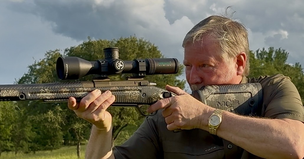 Dr. John McCall aiming a rifle fitted with a Stealth Vision optic outdoors