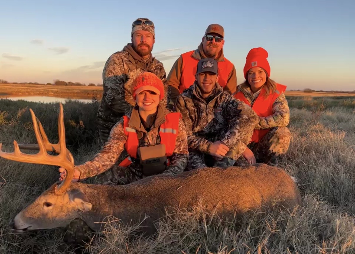 A group gathered around a harvested deer at sunset