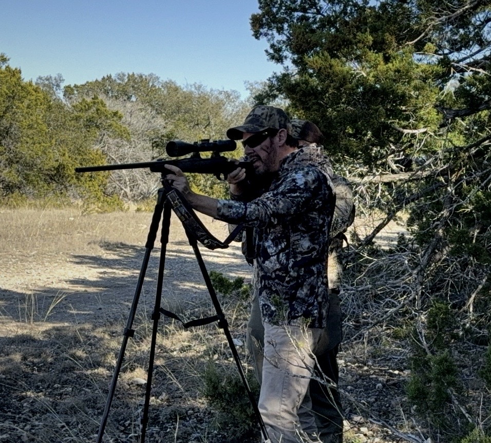 A hunter filming from a tripod in the field