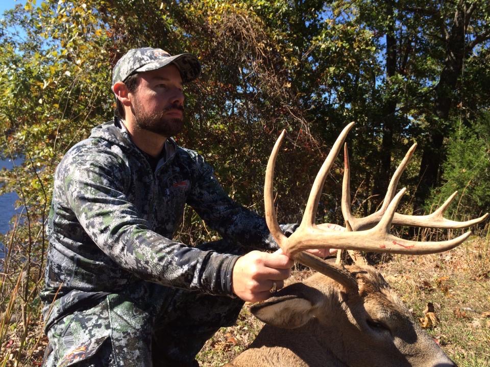 A hunter holding a mature whitetail outdoors